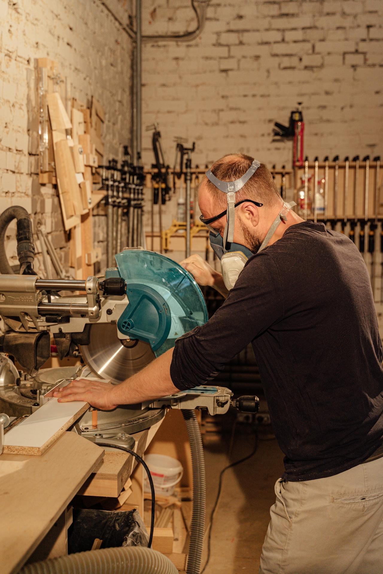 A man wearing mask working on wood at his studio